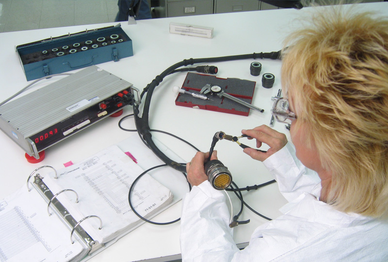 Employee making repairs to a connector at a bench